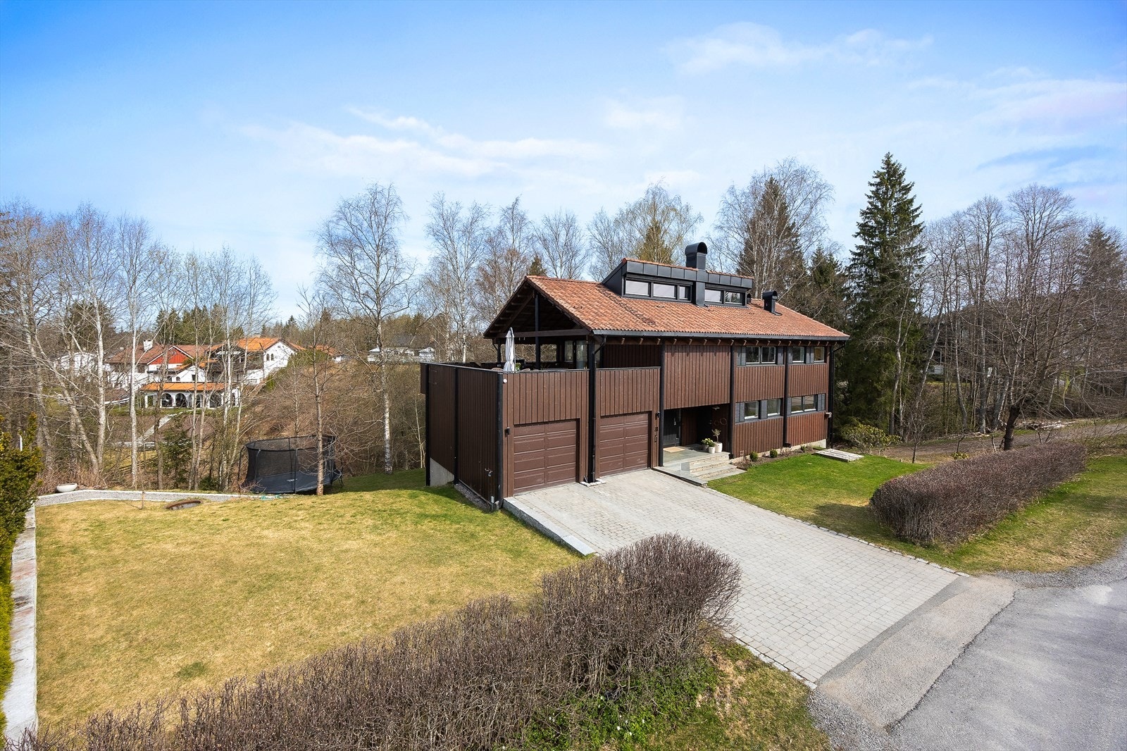 Hage på siden og fremsiden av huset med plen, klantstein, og hekk mot Gamle Trondheimsveg. Galleribilde