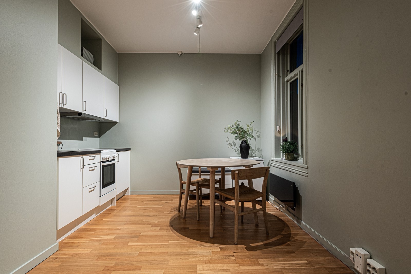 Kjøkkenet har hvit innredning fra Kitchens2all med glatte fronter, laminat benkeplate og nedfelt kum i rustfritt stål, samt kullfilterventilator - Benkekjøleskap er integrert, og det er i tillegg plass til frittstående komfyr Galleribilde