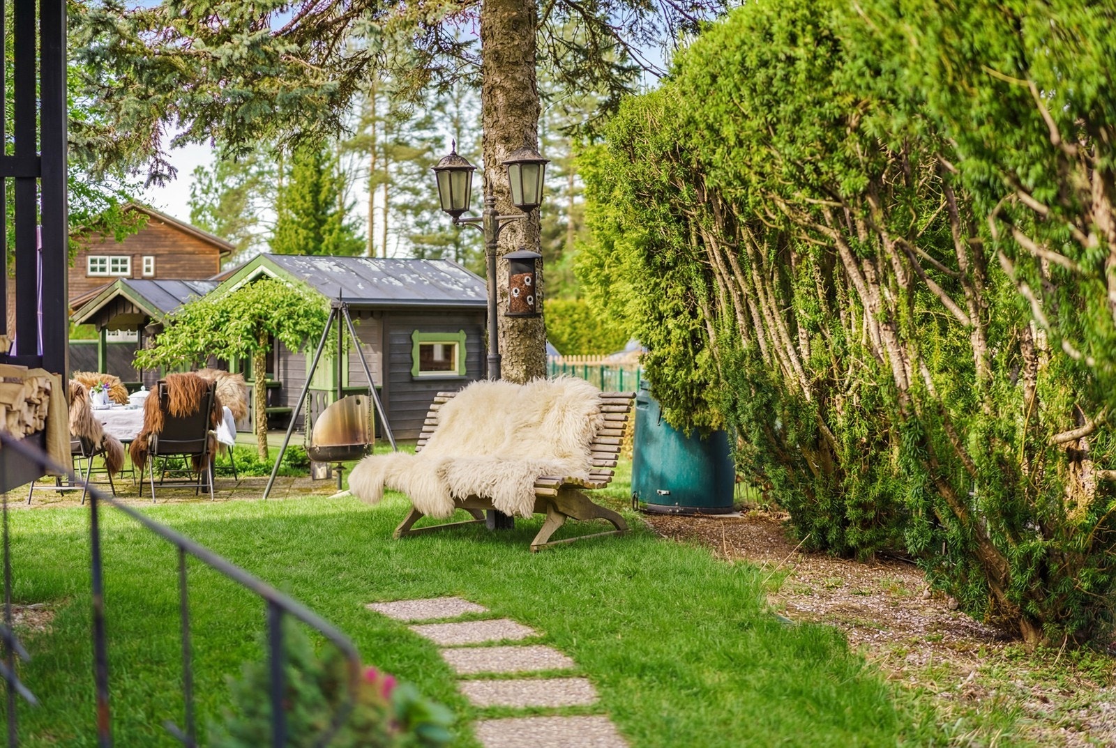 Eiendommen har flere trivelige utesoner med sitteplasser, beplantning, anneks m.m. Bildet har AI-redigert plen. Galleribilde