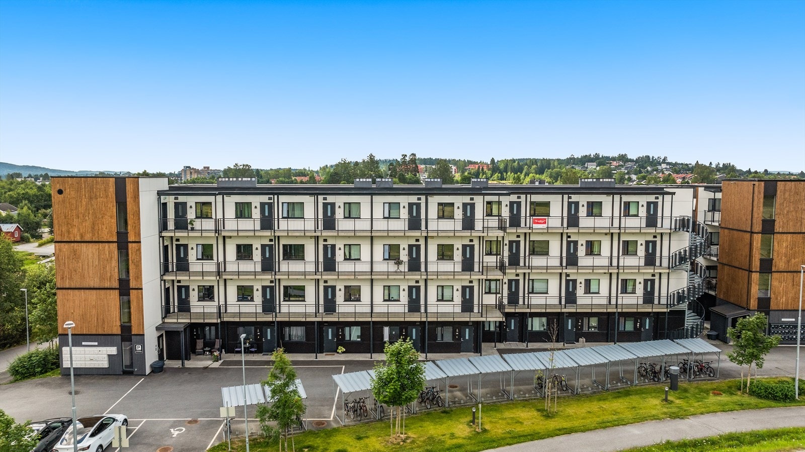 Fasade med inngangsparti, gjesteparkeringsplasser og sykkelparkering Galleribilde