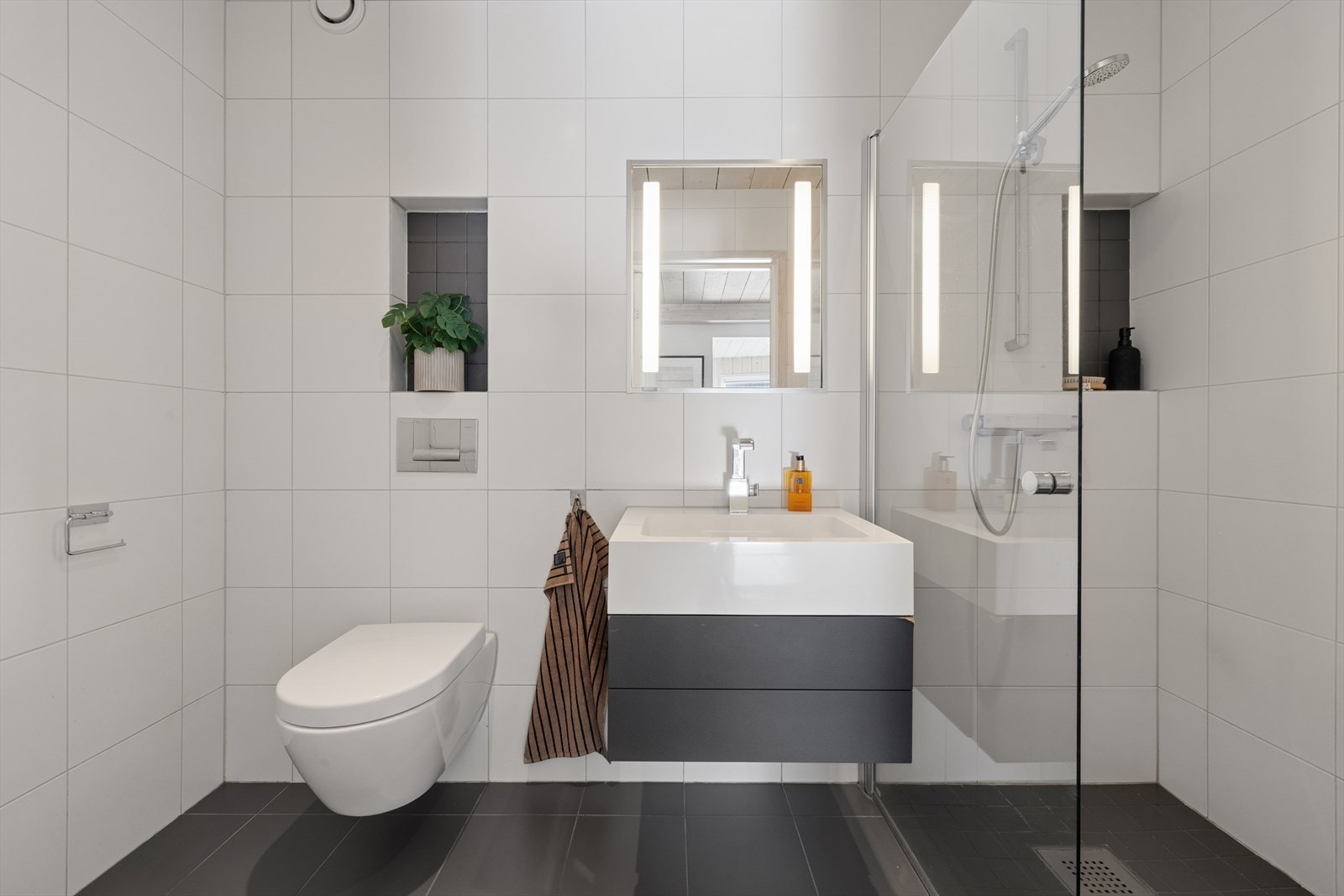 Badet i første etasje er flislagt og har dusjhjørne med svingbar glassdør, vegghengt toalett og vannbåren gulvvarme. Galleribilde