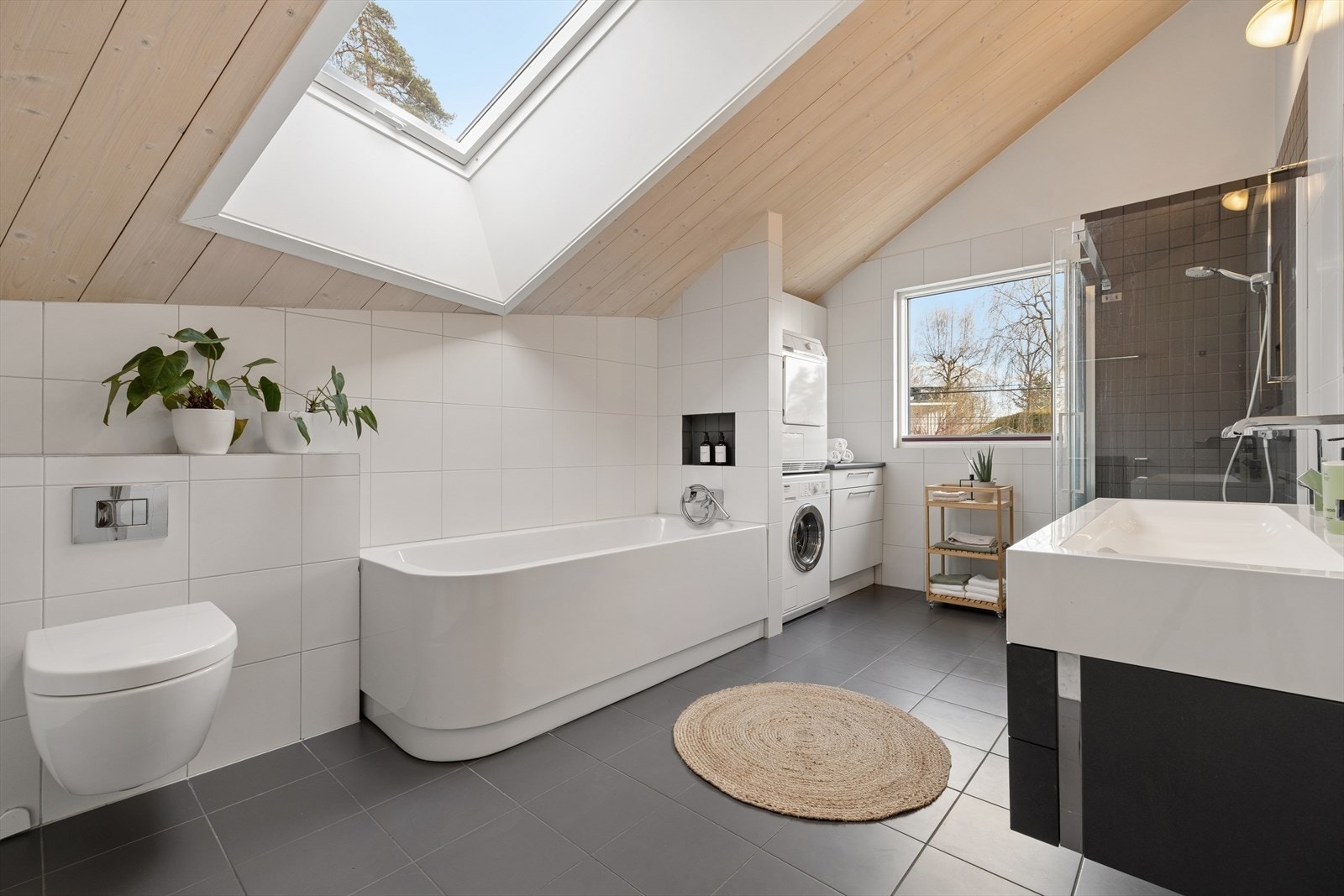Badet er funksjonelt og innredet med veggmontert toalett, dusjhjørne med skyvedør av glass samt badekar. Galleribilde