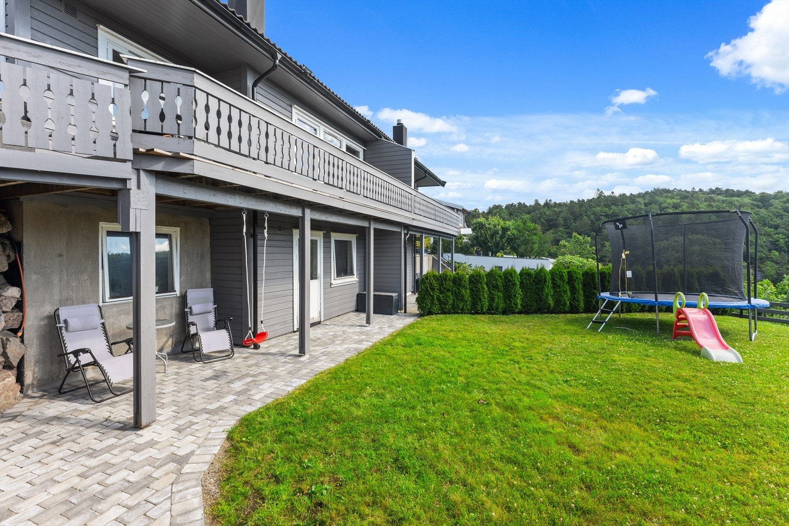 Pent opparbeidet med belegningsstein, busker og plen. Galleribilde