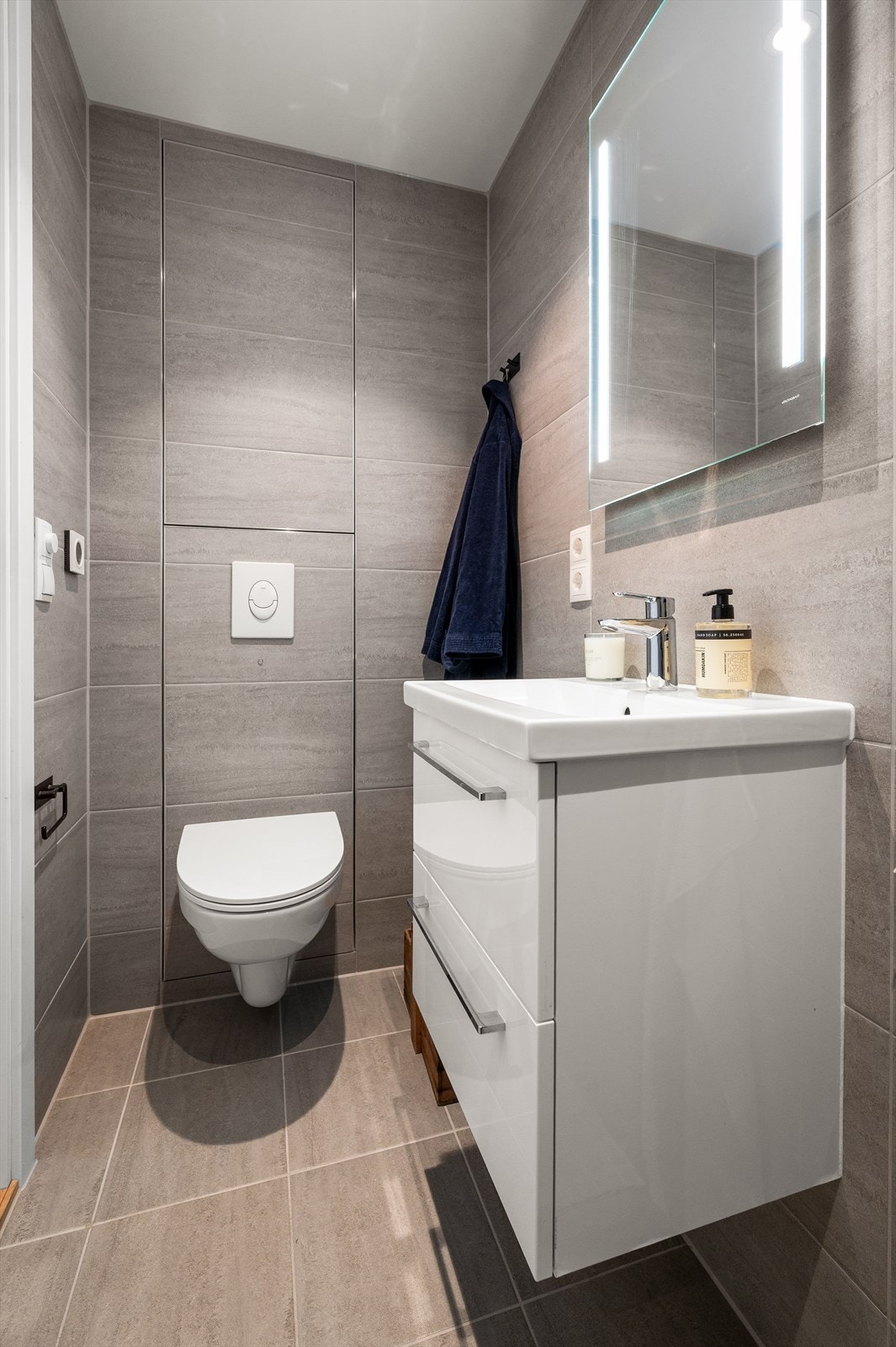 Badet har flislagt gulv med varme fra felles fjernvarmeanlegg, og vegghengt toalett. Galleribilde