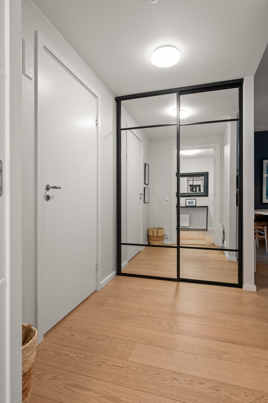 Innbydende entré med parkett på gulv og en stor skyvedørsgarderobe med speilfronter. Galleribilde