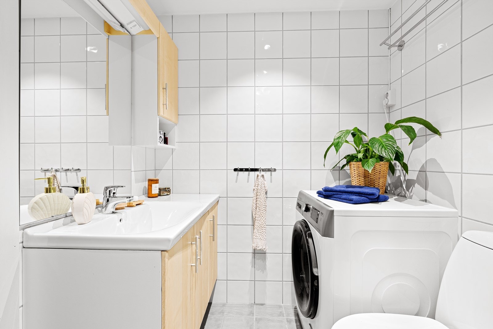 Badet er flislagt og fremstår praktisk innredet med dusjkabinett, servant og toalett. Galleribilde