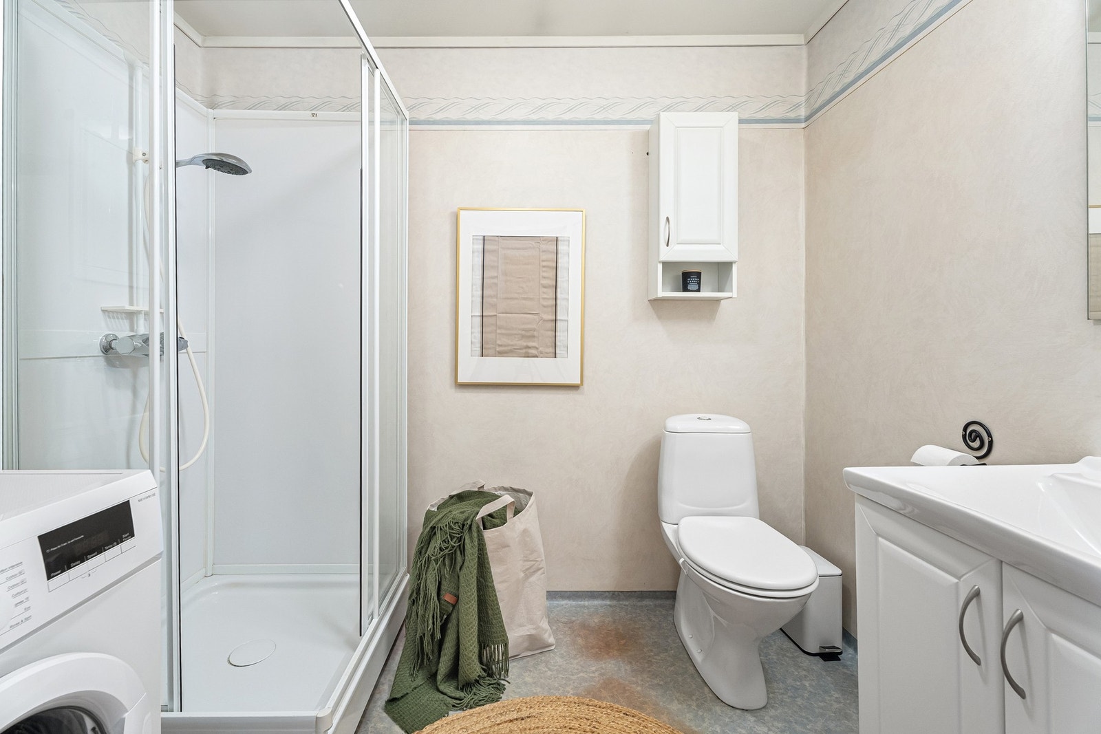 Bad innredet med dusjkabinet, servant, WC og oppsett for vaskemaskin Galleribilde
