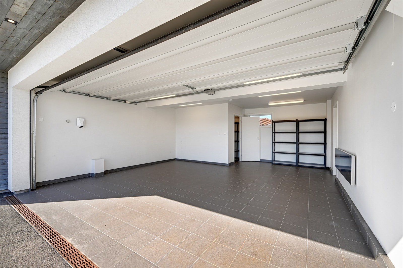 Integrert og isolert garasje med flislagt gulv og elbillader. Varmekabel er lagt i innkjørselen foran porten. Galleribilde