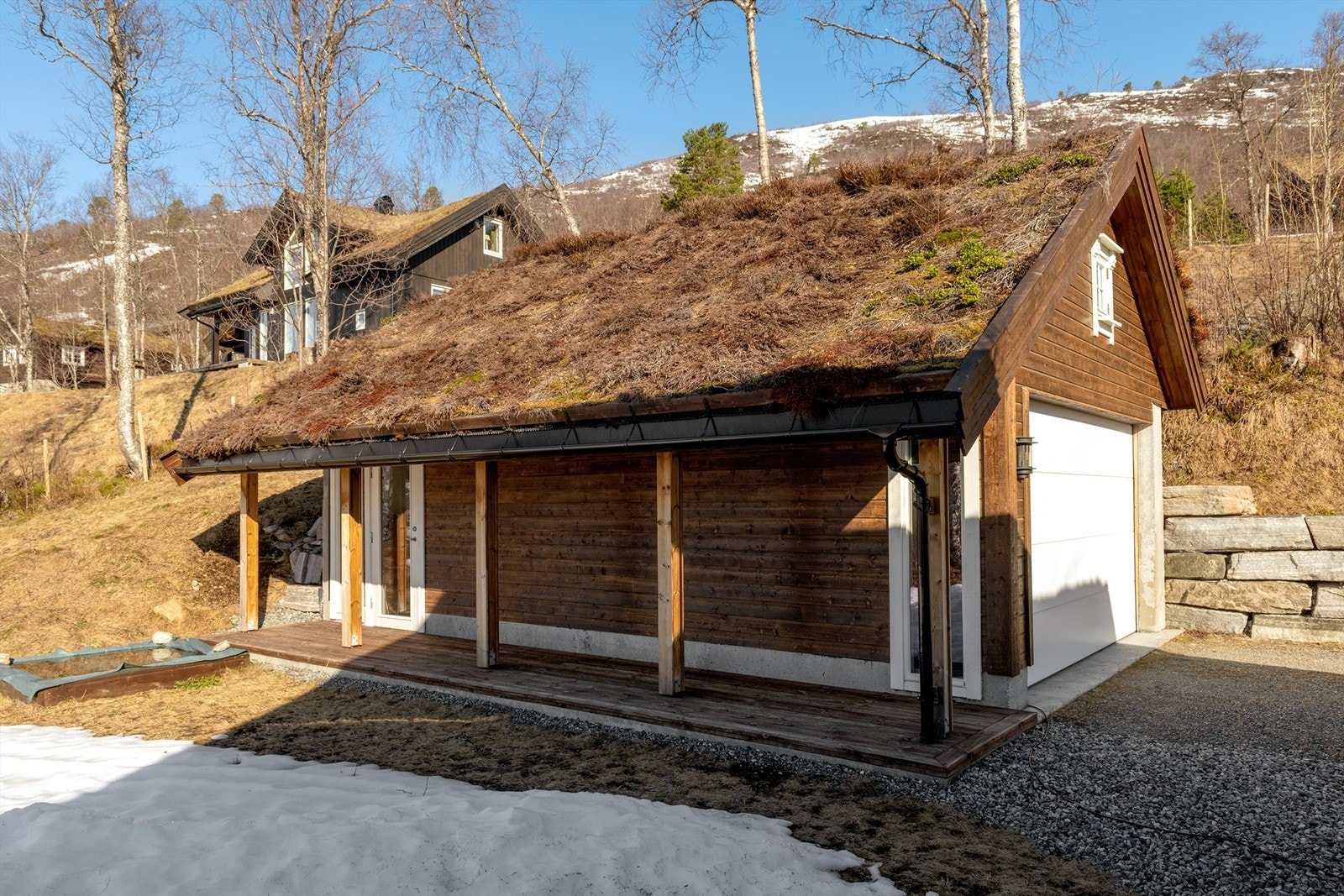 Garasjen er en solid bygning i betong- og trekonstruksjoner med torv på taket, i stil med hytta Galleribilde