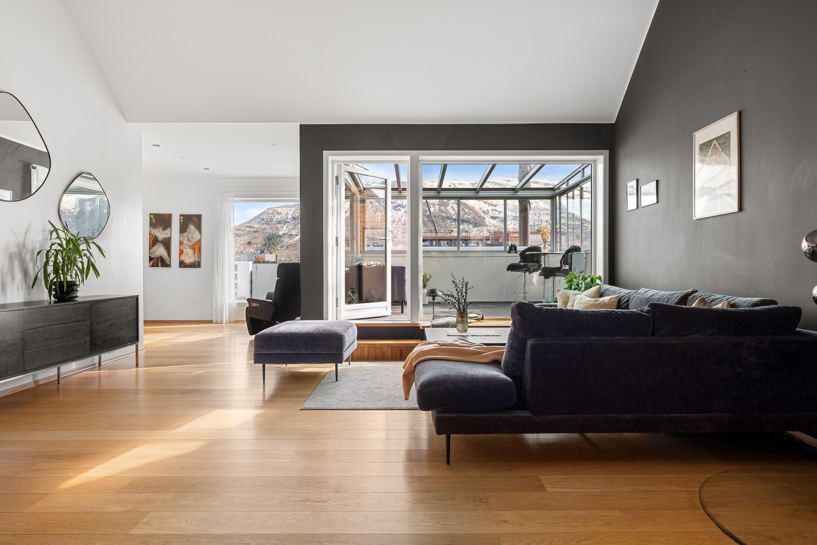 God plass i stuen til større sofa og annet møblement. De store vindusflatene slipper inn rikelig med naturlig lys.