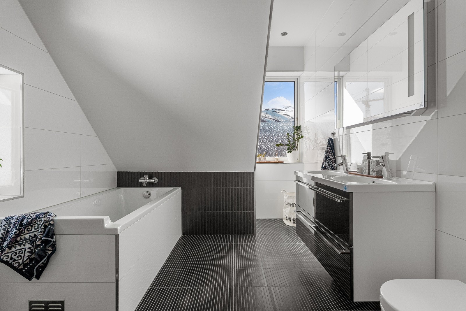 Moderne, flislagt bad. Utstyrt med både badekar og dusjhjørne med innfellbare glassdører.