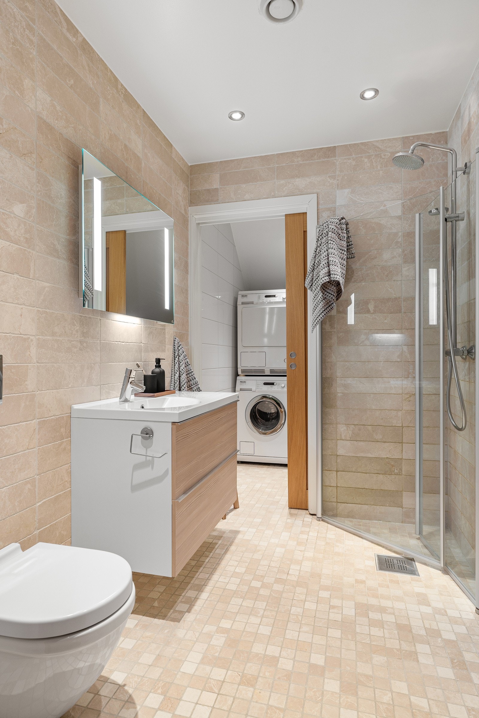 Bad nr 2 i lekker utførelse, med tidsriktige farger. Dusjhjørne med innfellbare glassdører, praktisk vegghengt toalett og baderomsinnredning med oppbevaringsplass.