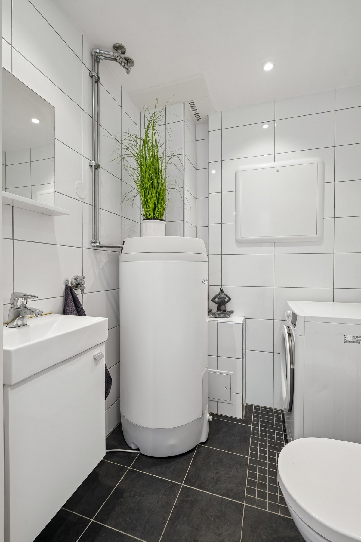 Bad/vaskerom er helfliset med elektriske varmekabler i gulvet. Slett himling med ledspotter. Innredet med servantskap, vegghengt toalett og opplegg for vaskemaskin. Galleribilde