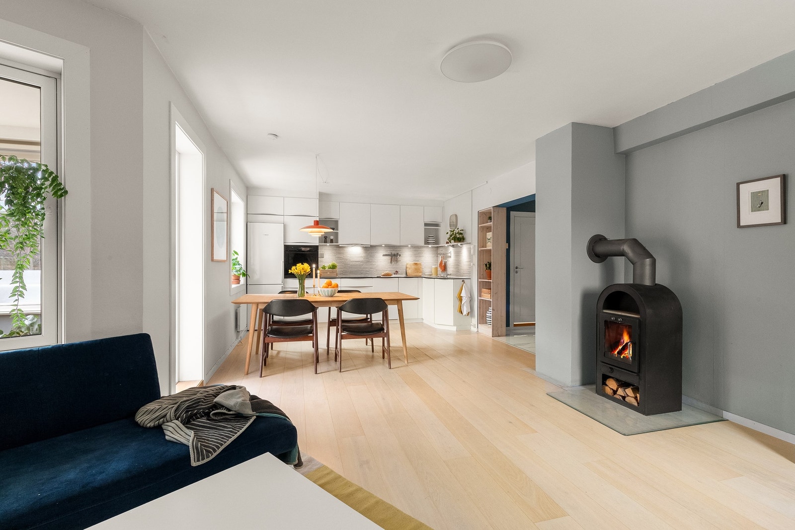 Leiligheten har en åpen og sosial løsning mellom kjøkken og stue, hvor vedovnen skaper ekstra hygge. Foto: Fotostallen v/ Lars-Petter Skillestad Galleribilde