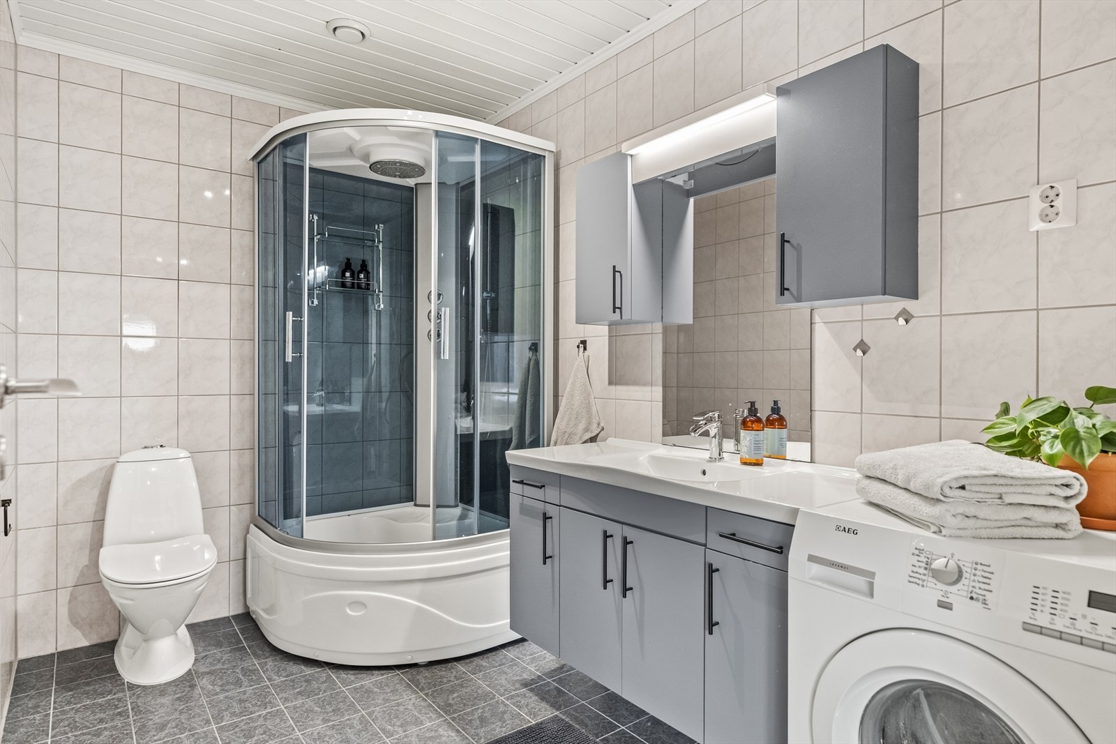 Badet er stort, og pent flislagt med lyse fliser på veggene og grå gulvfliser. Galleribilde