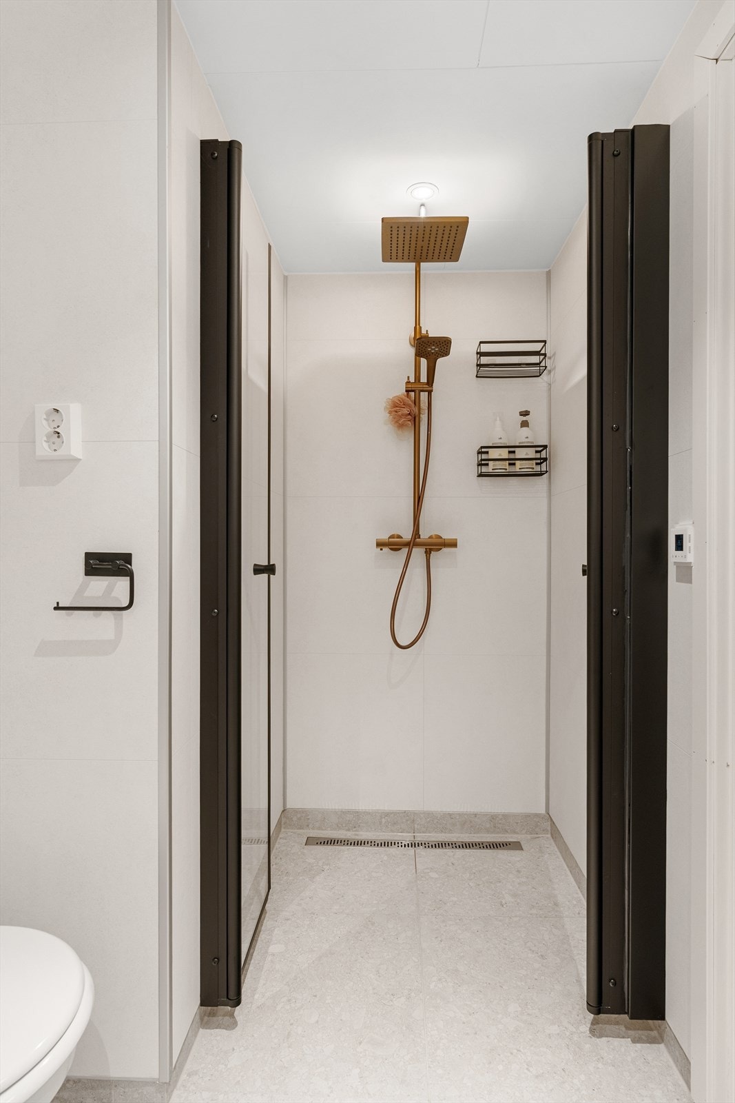 Rommet har dusjløsning med takdusj og vegghengt toalett, samt servant med underskap. Badet fremstår som nytt og tidsriktig, med løsninger som gir både funksjonalitet og et moderne uttrykk. Galleribilde