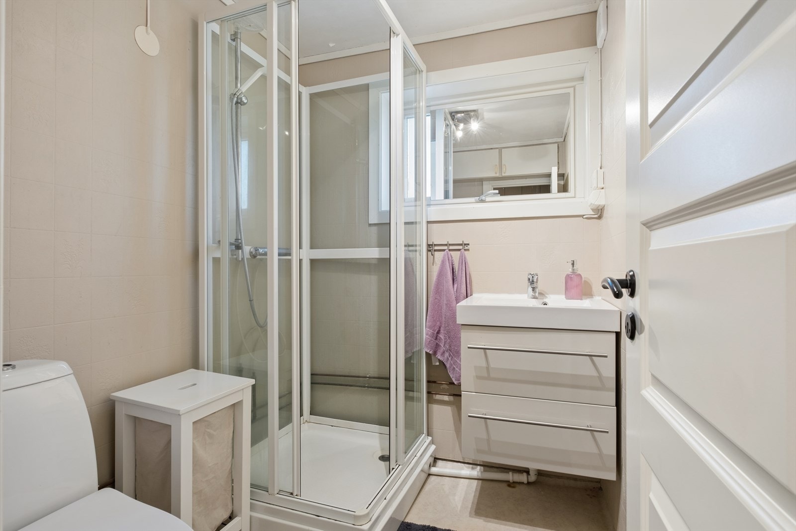 Badet i første etasje er et eldre rom med belegg på gulv, våtromstapet på veggene, dusjkabinett og mekanisk avtrekk. Galleribilde