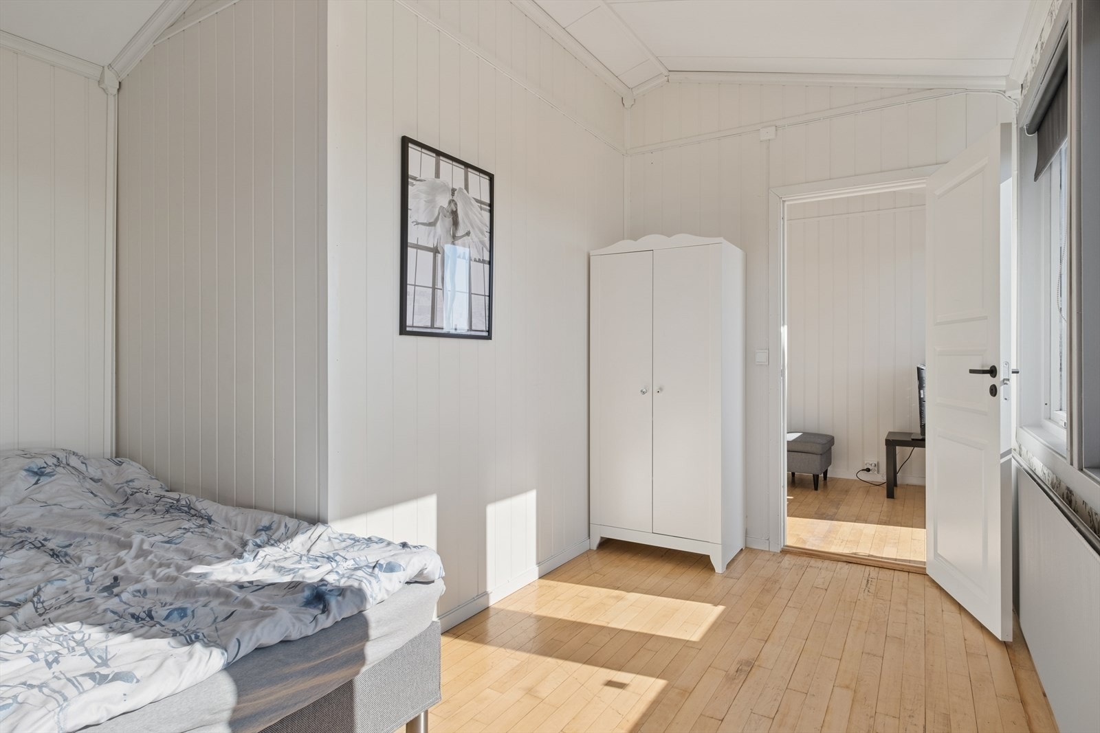Lyst soverom med tregulv og panel på veggene. Galleribilde