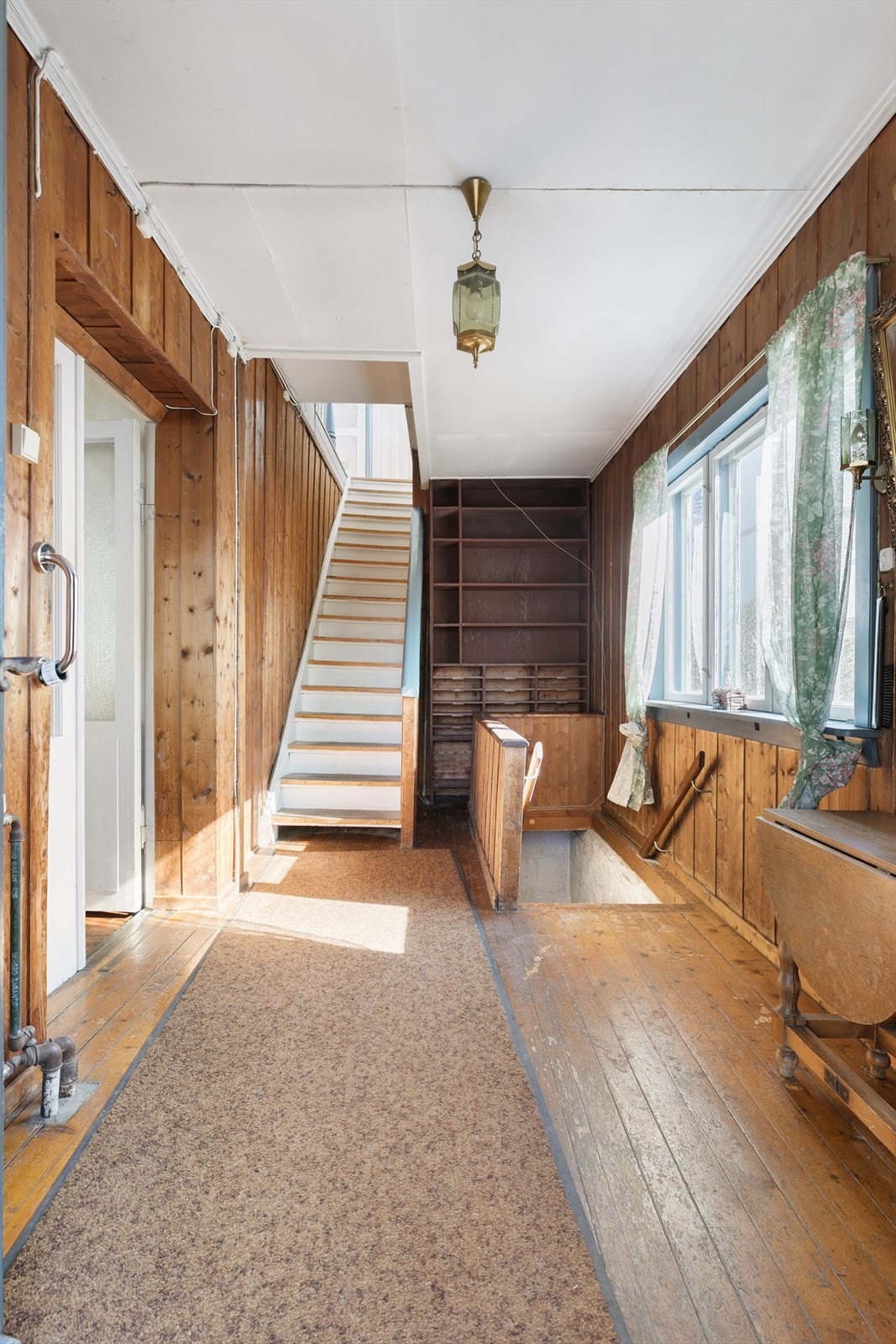 Gangen har trepanel, originale tregulv og detaljer som vitner om husets historie. Trappeløpet leder naturlig videre opp i 2. etasje og kjeller, mens store vindusflater slipper inn godt med dagslys. Galleribilde