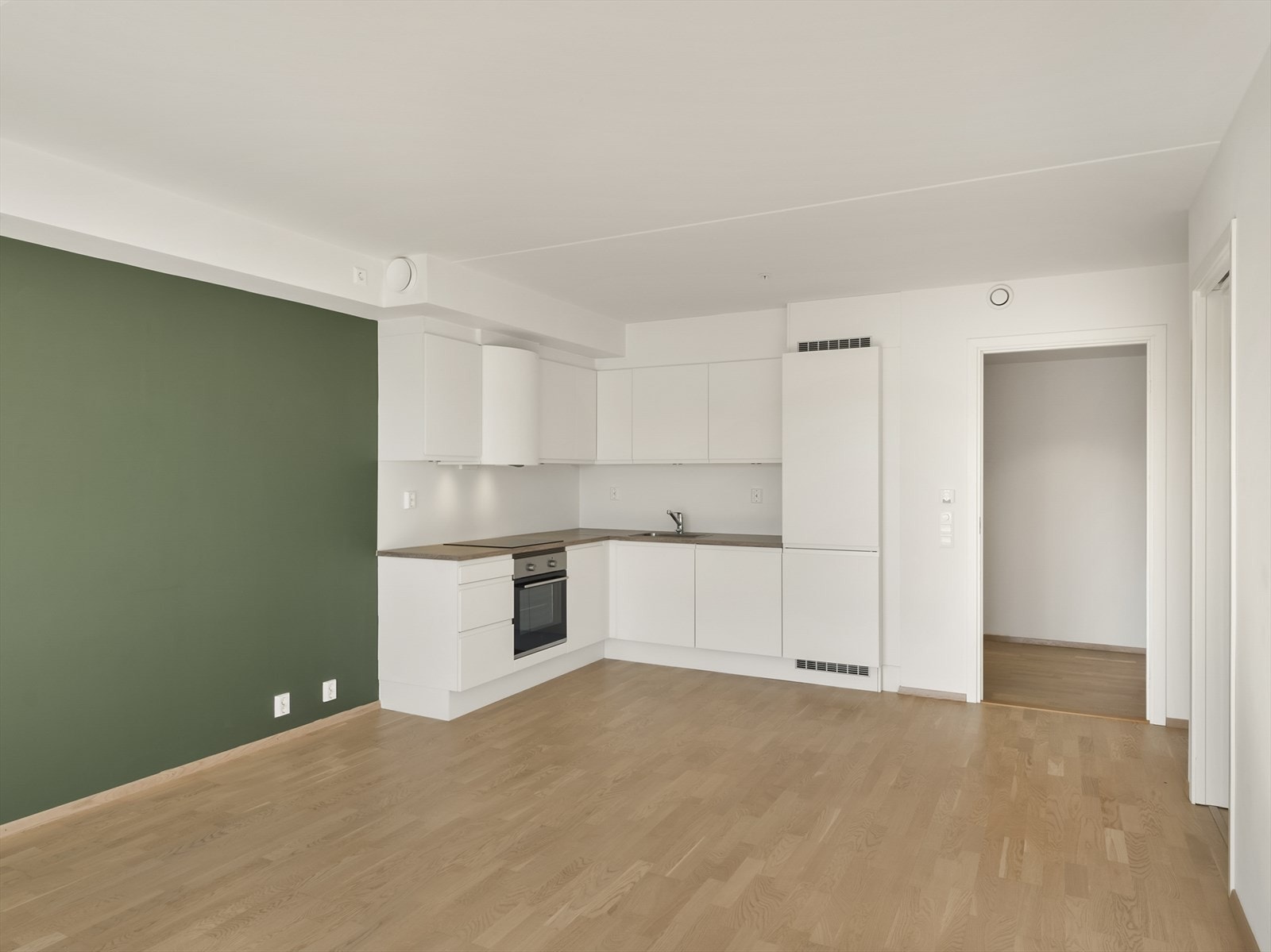 Den åpne løsningen mellom stue og kjøkken gir en lys og sosial sone med plass til sofa og et lite spisebord. Galleribilde