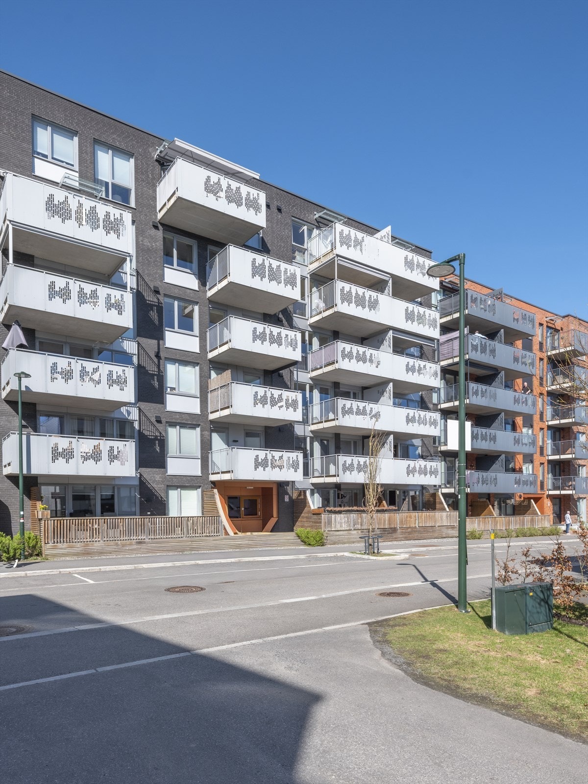 Bygget har en moderne fasade med en kombinasjon av teglstein, treverk og mur. Galleribilde