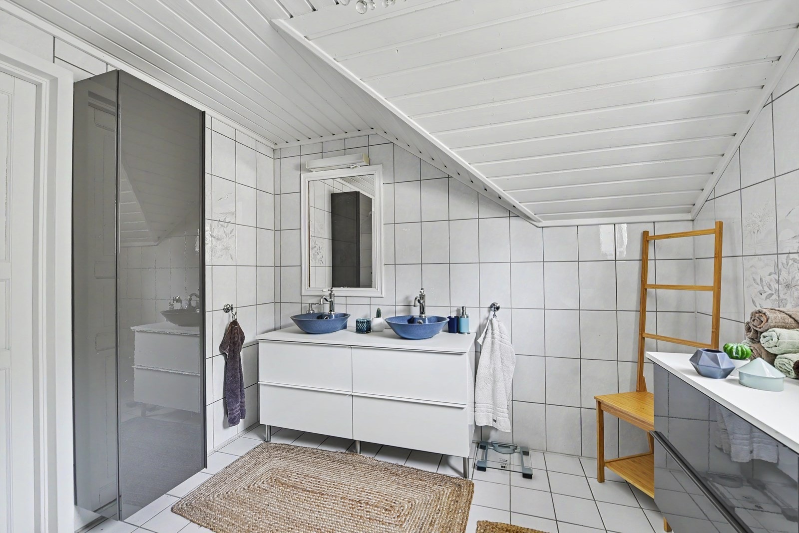 Romslig bad i loftsetasjen med flislagte overflater, gulvvarme og en moderne, dobbel servant. Galleribilde