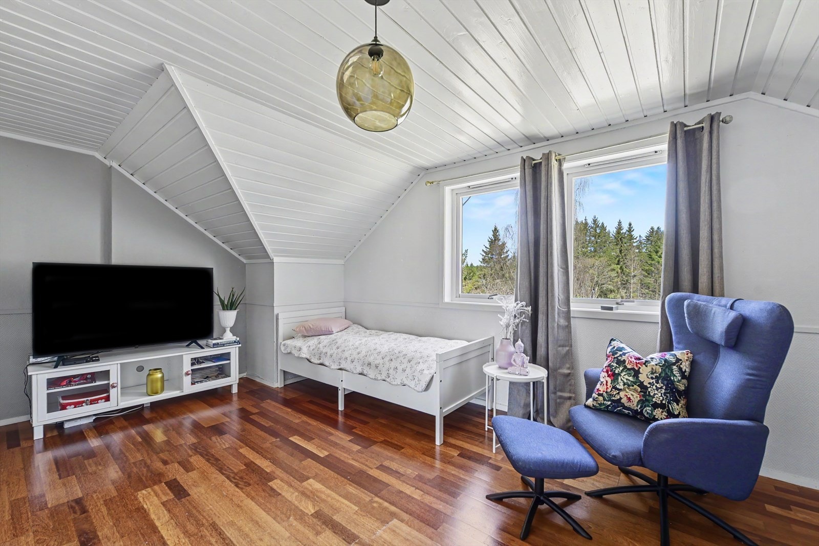 Rommet har parkett på gulvet og panel i himlingen, og vinduene gir utsikt mot skogen. Galleribilde