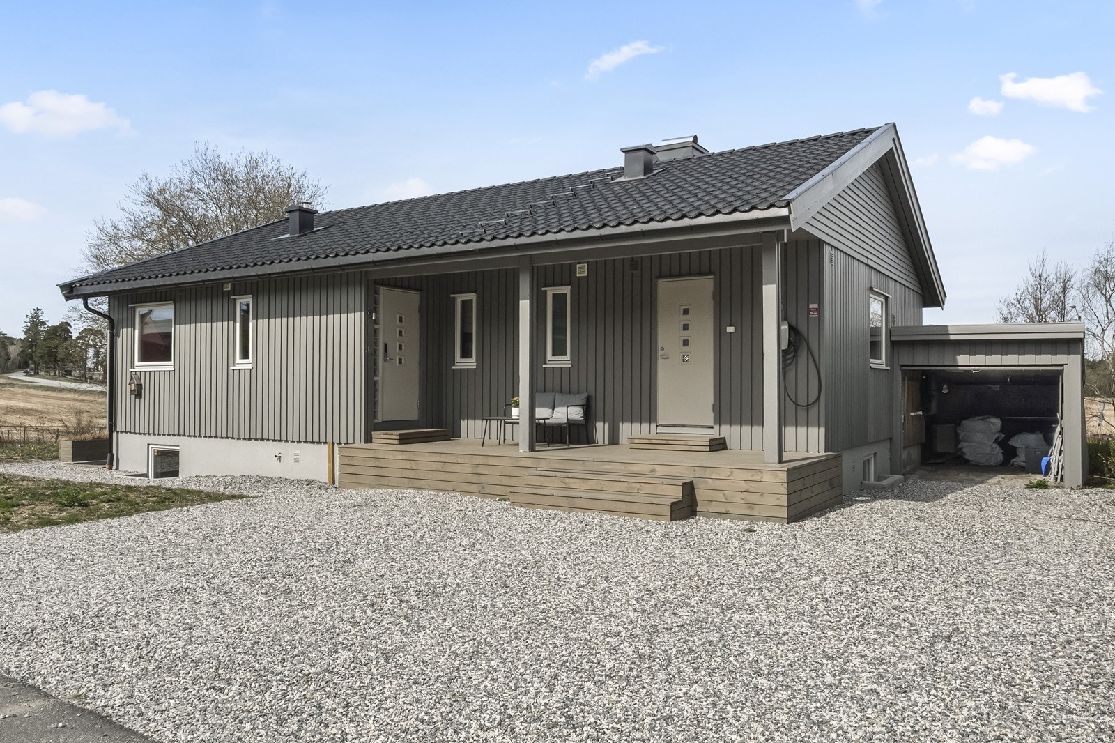 Enebolig fra 1975 med integrert garasje og gruslagt gårdsplass. Galleribilde