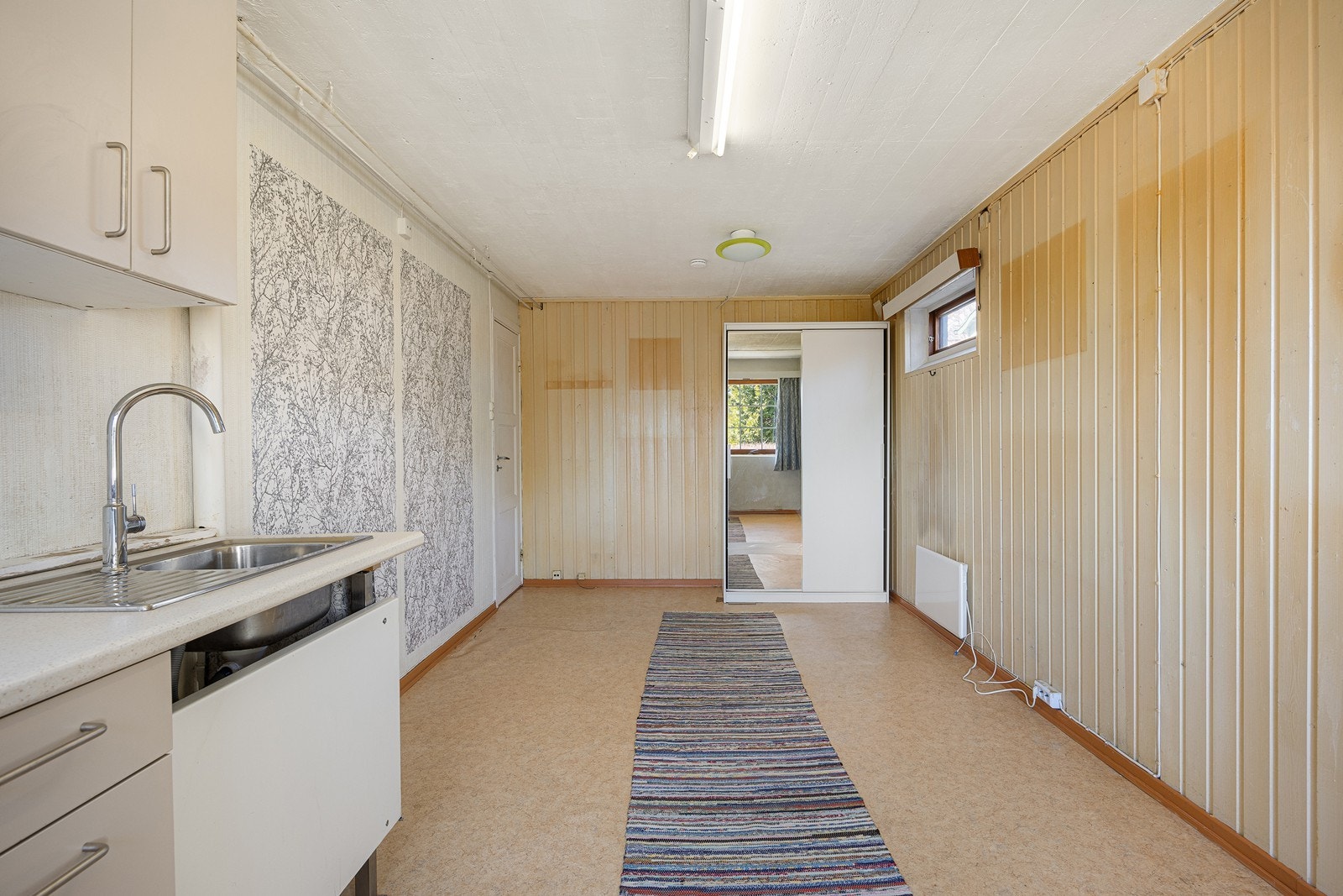 Det innredede rommet har store vinduer sørger for rikt, naturlig lysinnslipp. Det er tapetserte vegger og belegg på gulvet. I rommet er det også en skyvedørsgarderobe. Galleribilde