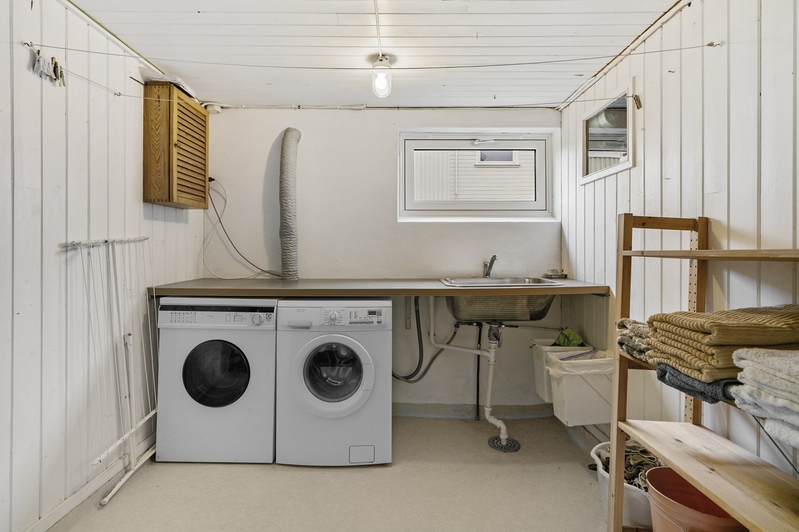 Praktisk vaskerom med opplegg for vaskemaskin og tørketrommel. Vaskerommet har benkeplate og utslagsvask Galleribilde