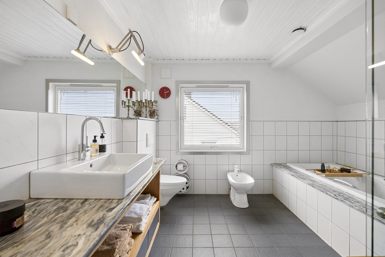 Badet er innredet med veggehengt toalett, bidé, servant i baderomsmøbel, dusjhjørne og badekar Galleribilde