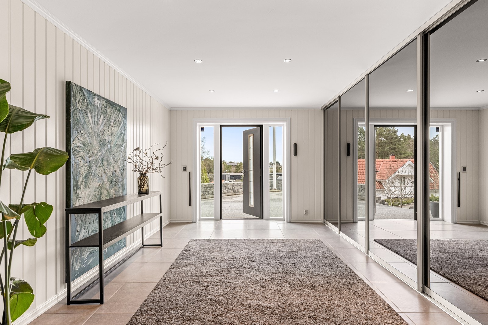 Innbydende hall i underetasjen med flislagt gulv og stor skyvedørsgarderobe. Galleribilde