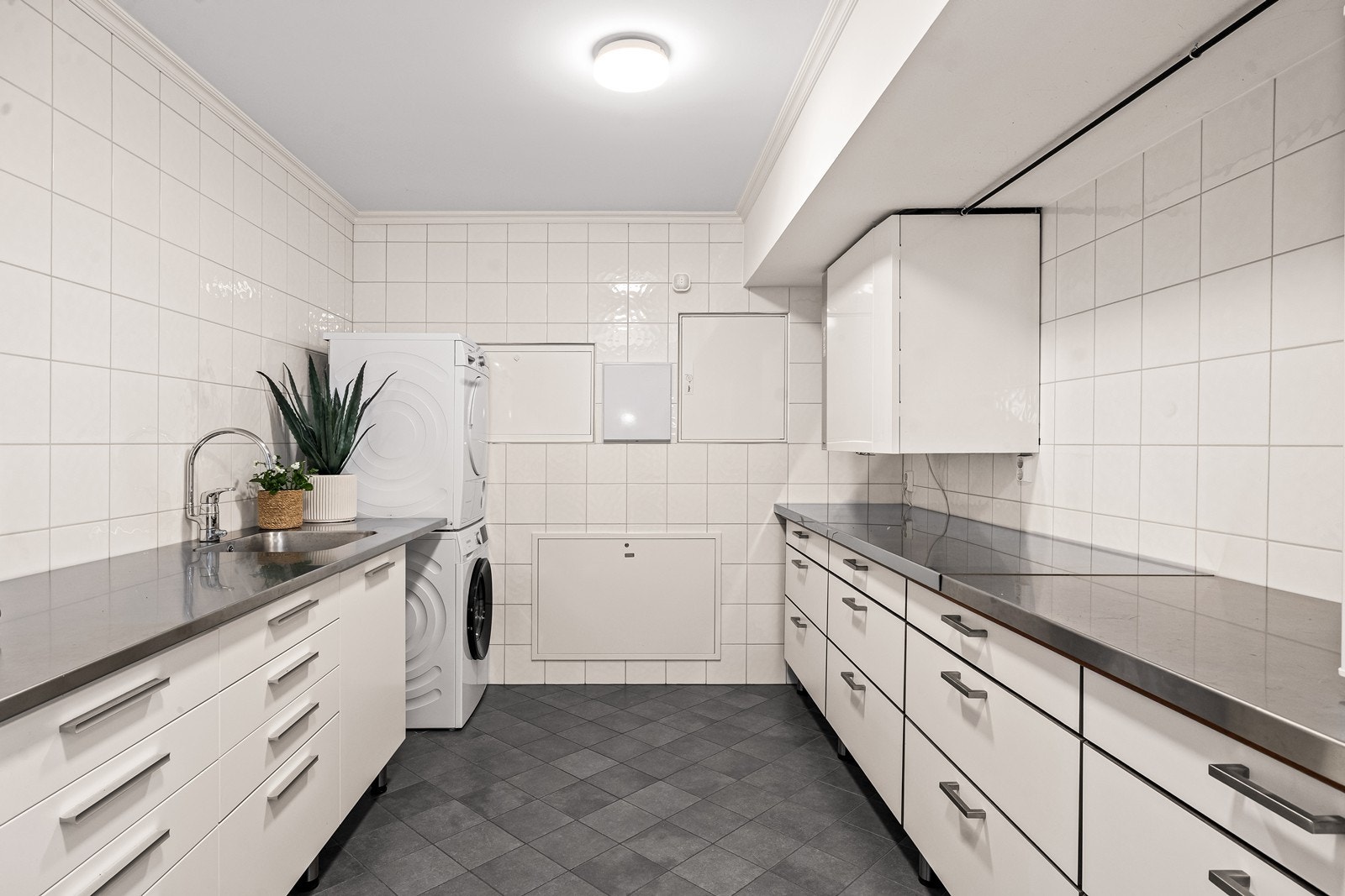 Praktisk og romslig vaskerom med flislagt gulv, vannbåren gulvvarme og rikelig med skap- og benkeplass. Galleribilde
