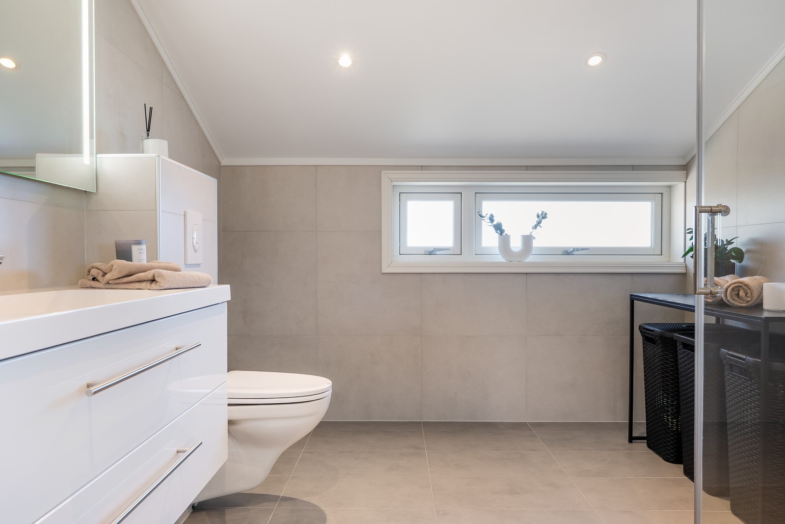 Badet er plassert i boligens øvre etasje og fremstår linnbydende med fliser og farger i lyse toner. Galleribilde