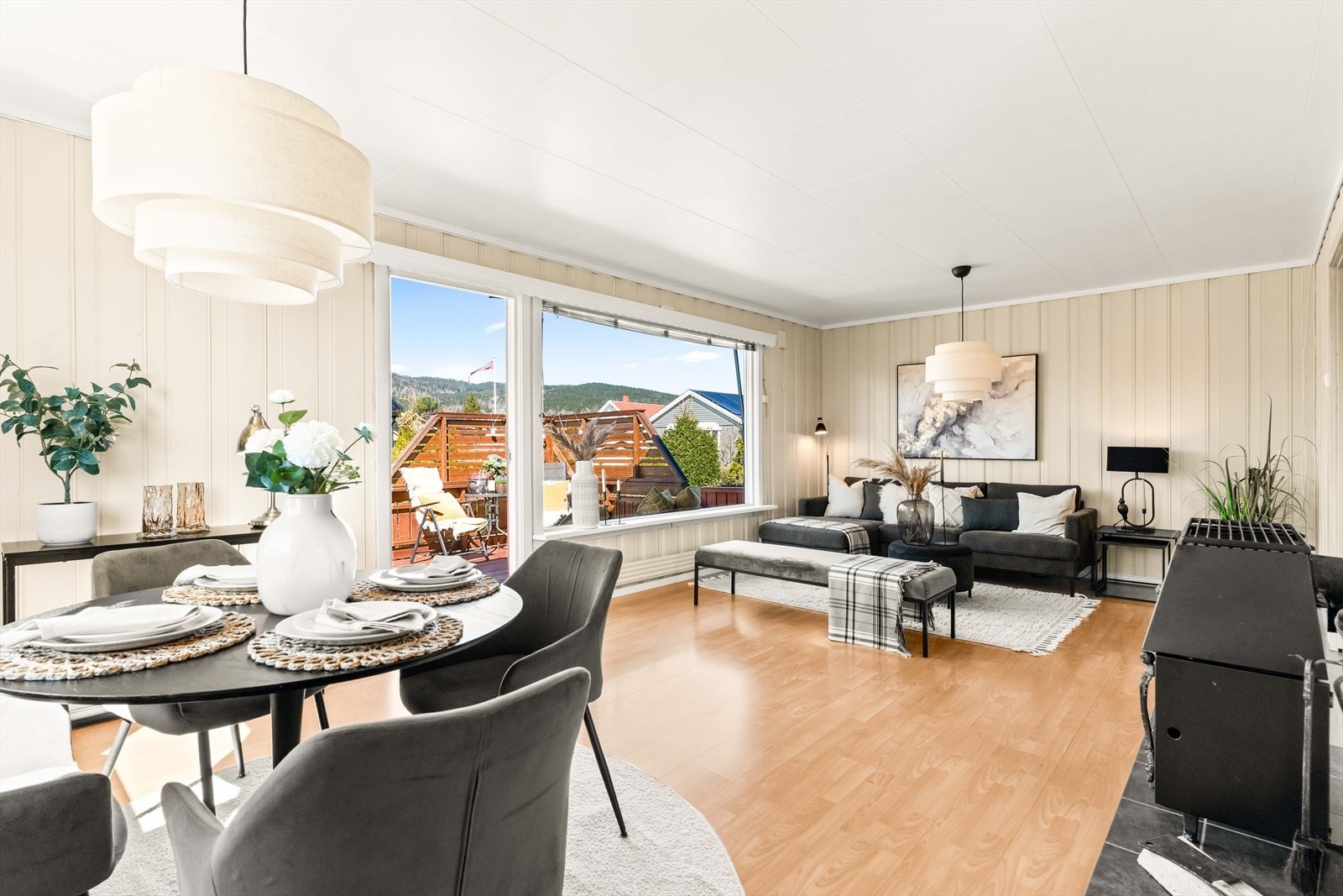 Dagslyset som strømmer inn via store vinduer gjenspeiles fint i de lysmalte veggene, og stuen har laminat på gulvet. Galleribilde
