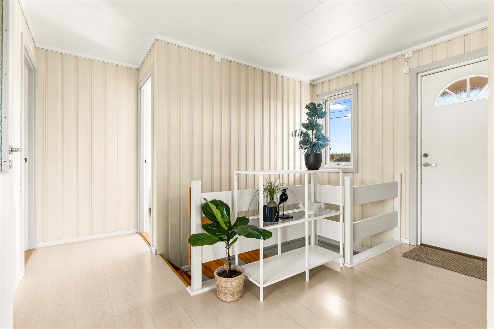 Vel inne er det en fin entré med lysmalt panel på veggene og lyst, matchende laminat på gulvet. Galleribilde
