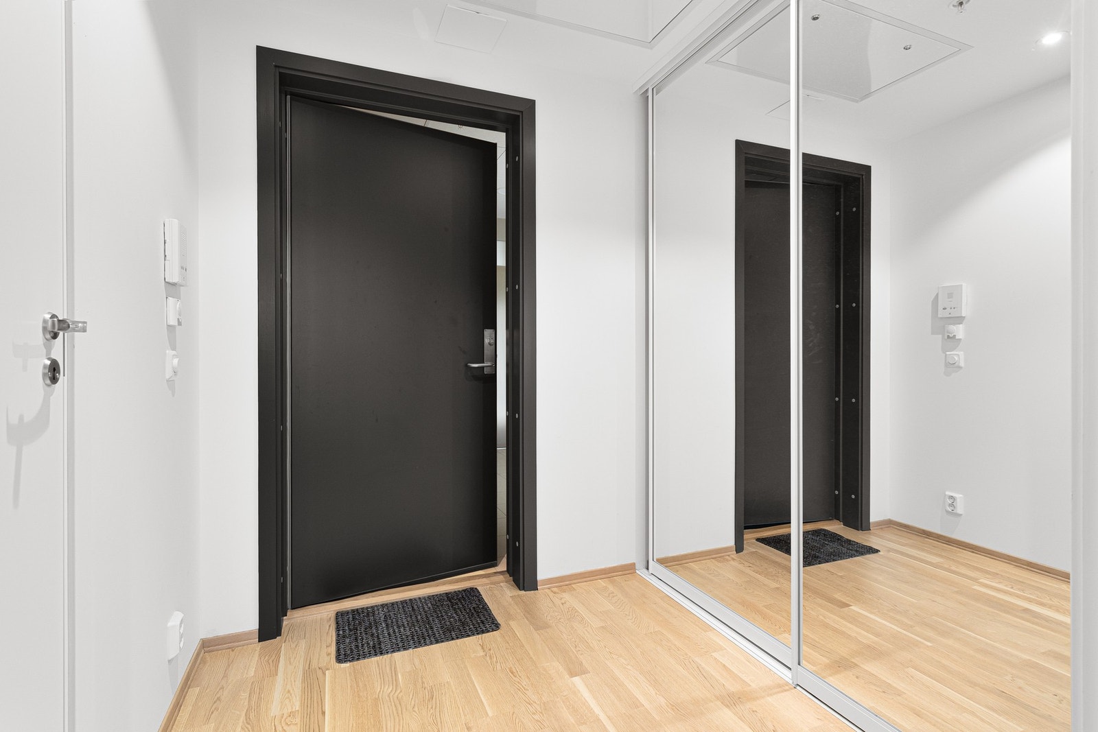 En stor og plassrik entré som er innredet med praktisk skyvedørsgarderobe som kommer godt med til oppbevaring. Galleribilde