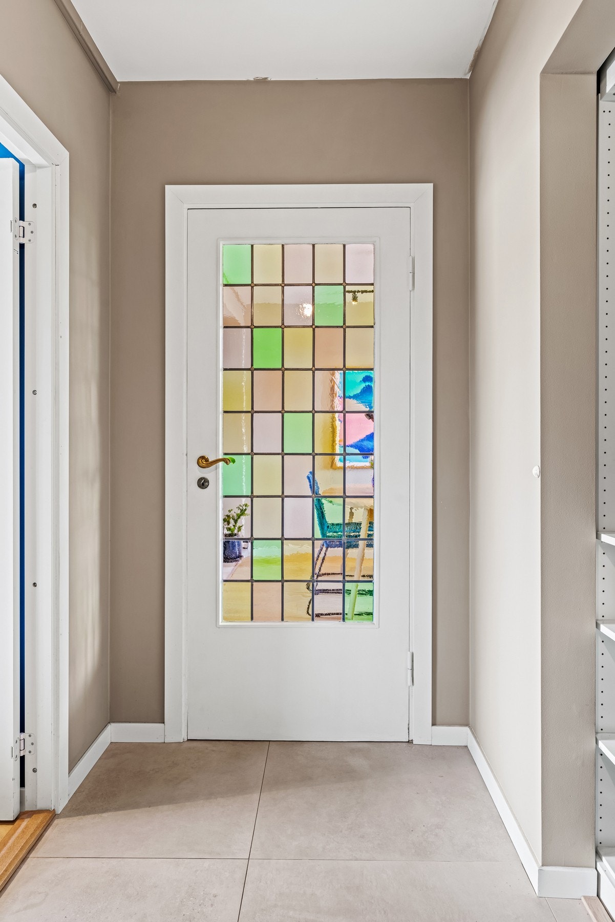 Glassdøren med farget glass skaper en lun atmosfære og lysspill mellom gang og stue. Galleribilde