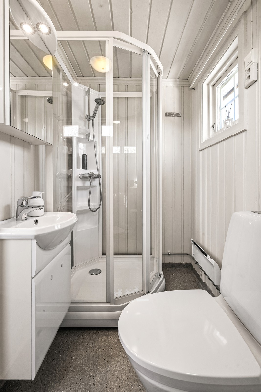 Badet er etablert der det tidligere var to boder. Rommet har belegg på gulv og panel på vegger. Badet er innredet med toalett, dusjkabinett og servant. Ventilasjon skjer via en elektrisk styrt vifte. Galleribilde