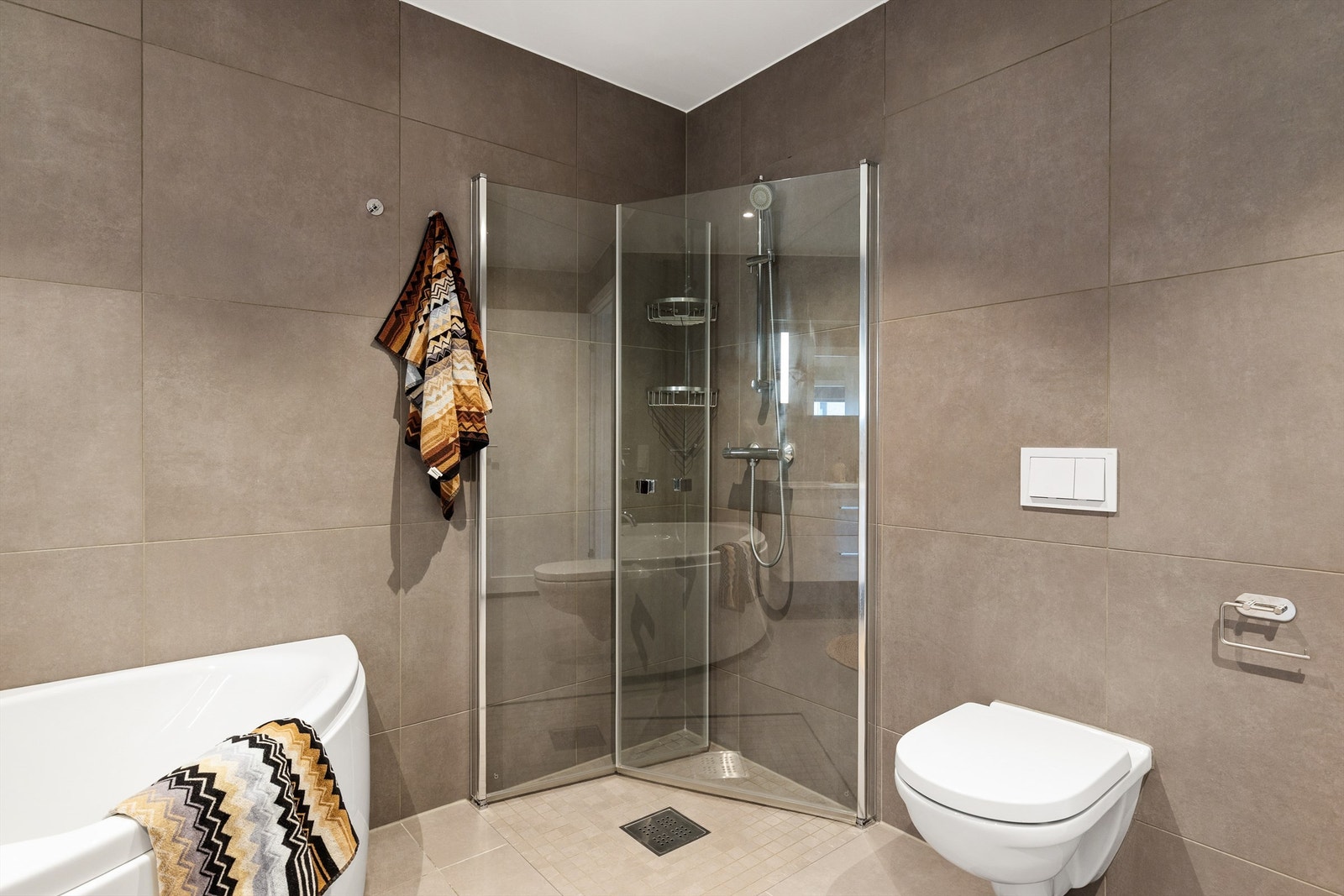 Badet er utstyrt med vegghengt toalett og dusjplass med inn- og utadslående dusjvegger. Galleribilde
