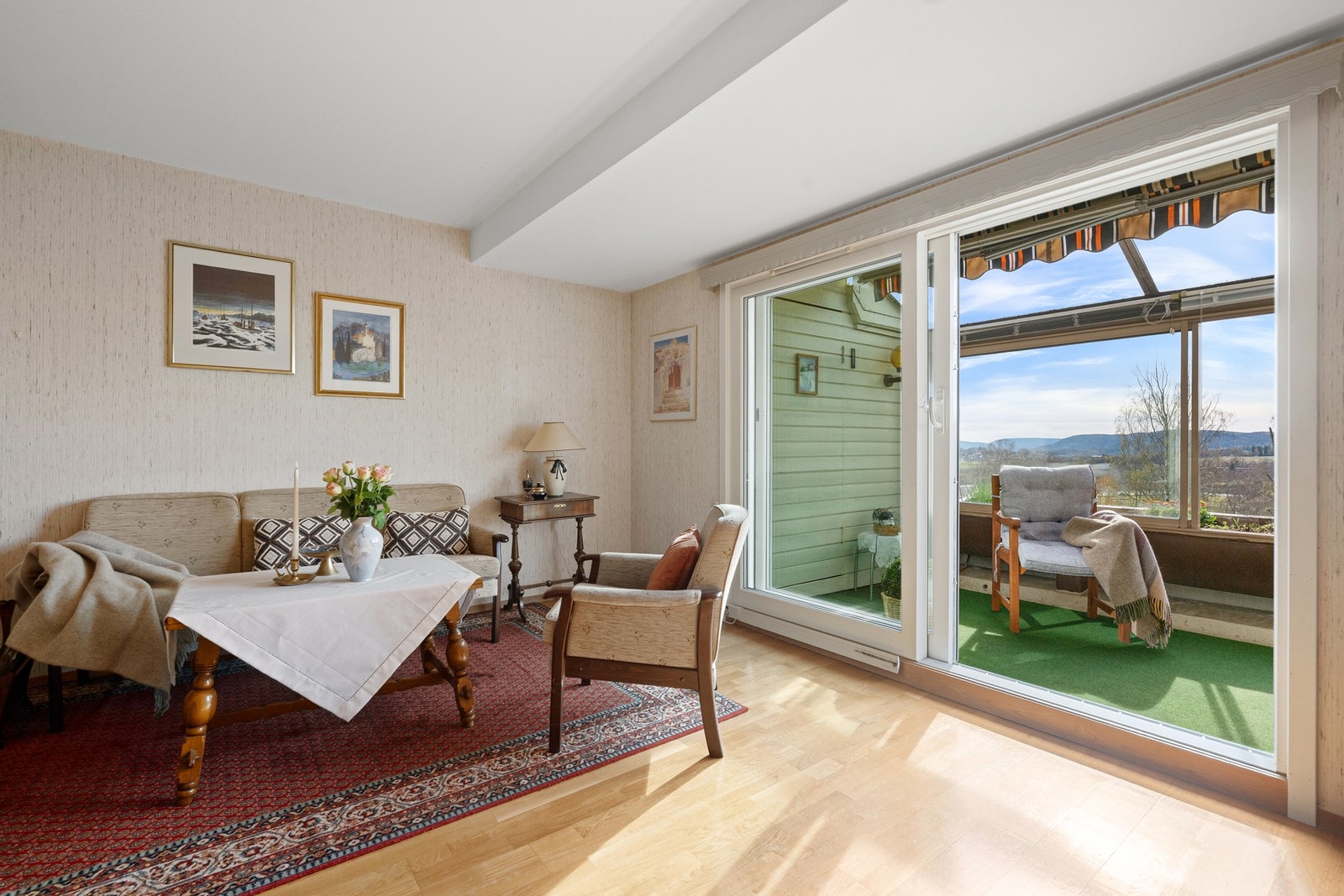 Lys stue med utgang til sydvendt, innglasset balkong og nyere skyvedørsløsning som slipper inn rikelig med dagslys. Galleribilde