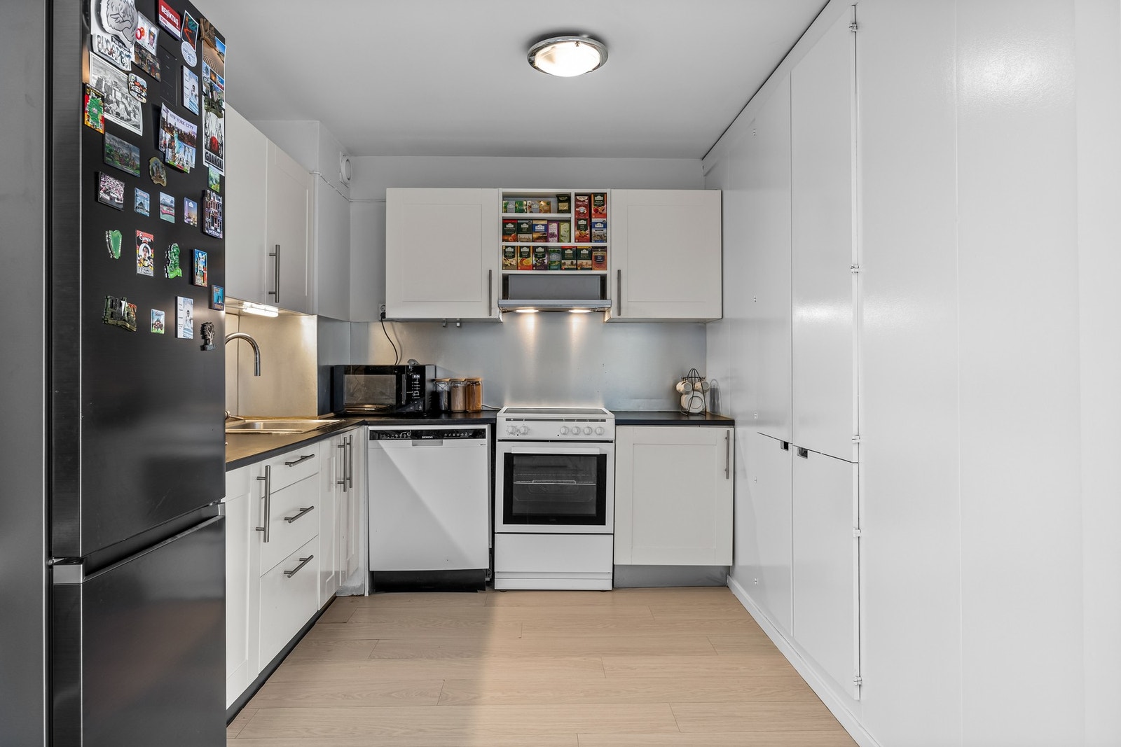 Kjøkken med effektiv planløsning, ventilator med kullfilter over kokesone og gode nisjeløsninger for komfyr, oppvaskmaskin og kjøl-/fryseskap. Galleribilde