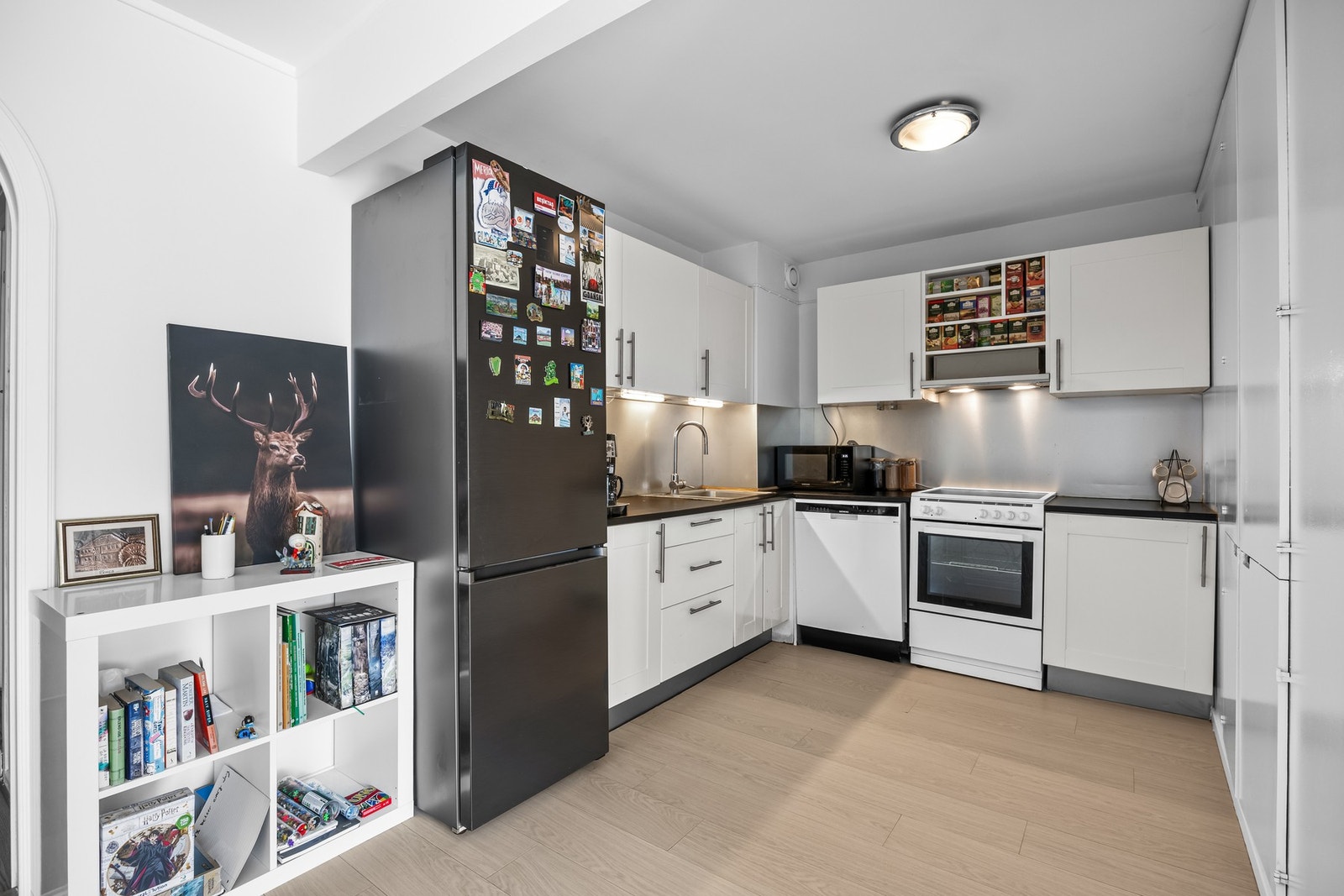 Funksjonell kjøkkenløsning med nedfelt oppvaskkum, opplegg for hvitevarer og slitesterk stålplate over benkeplaten. Galleribilde