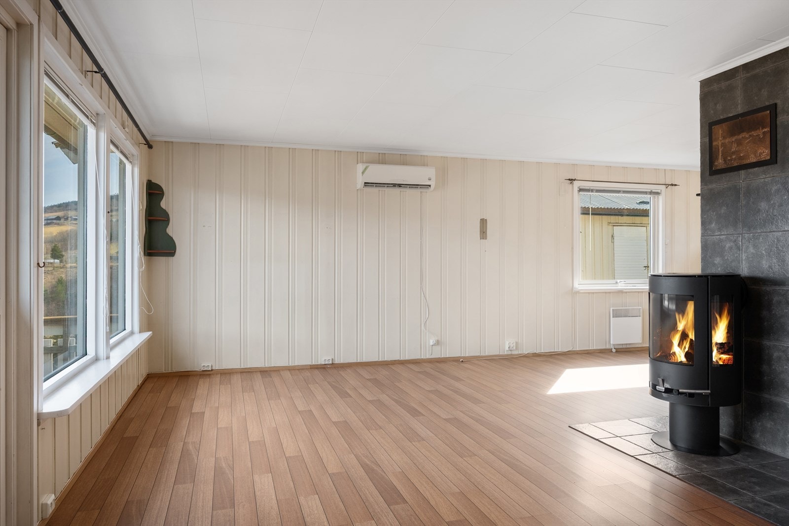 Store vindusflater og panelkledde vegger gir stuen et lyst og trivelig preg. Galleribilde