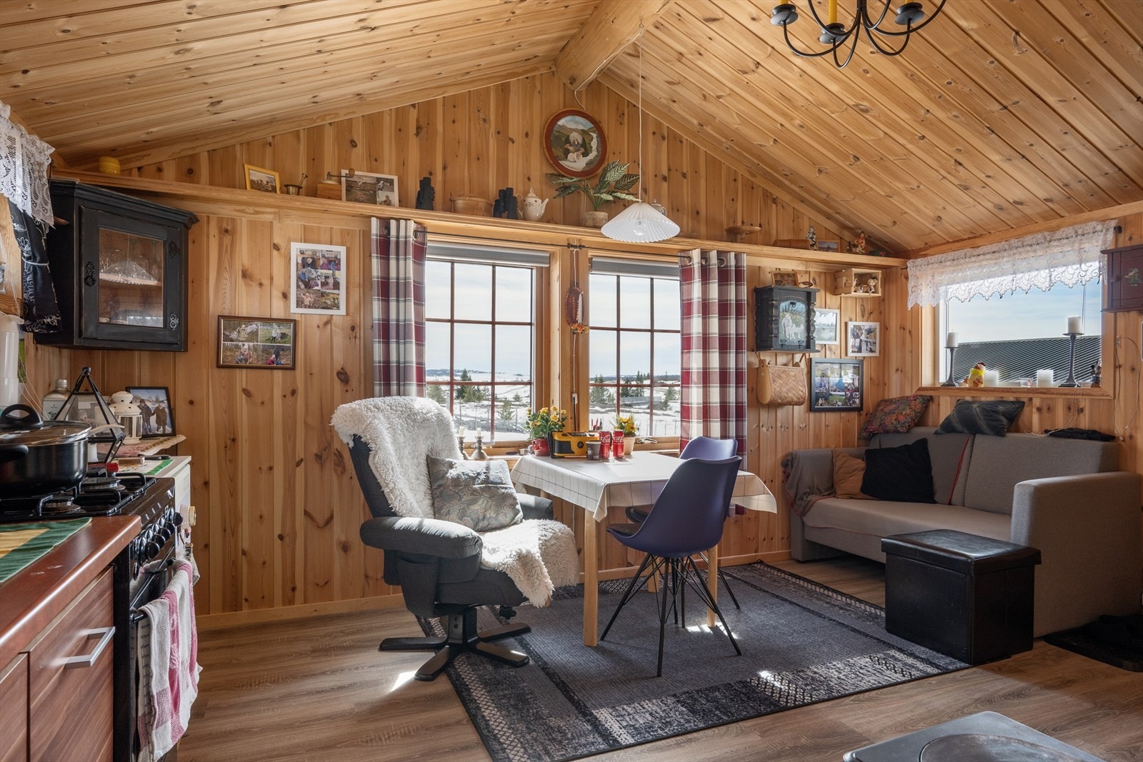 Inne i annekset er det en lys og trivelig stue med åpen kjøkkenløsning og panel i tak og på vegger. Galleribilde