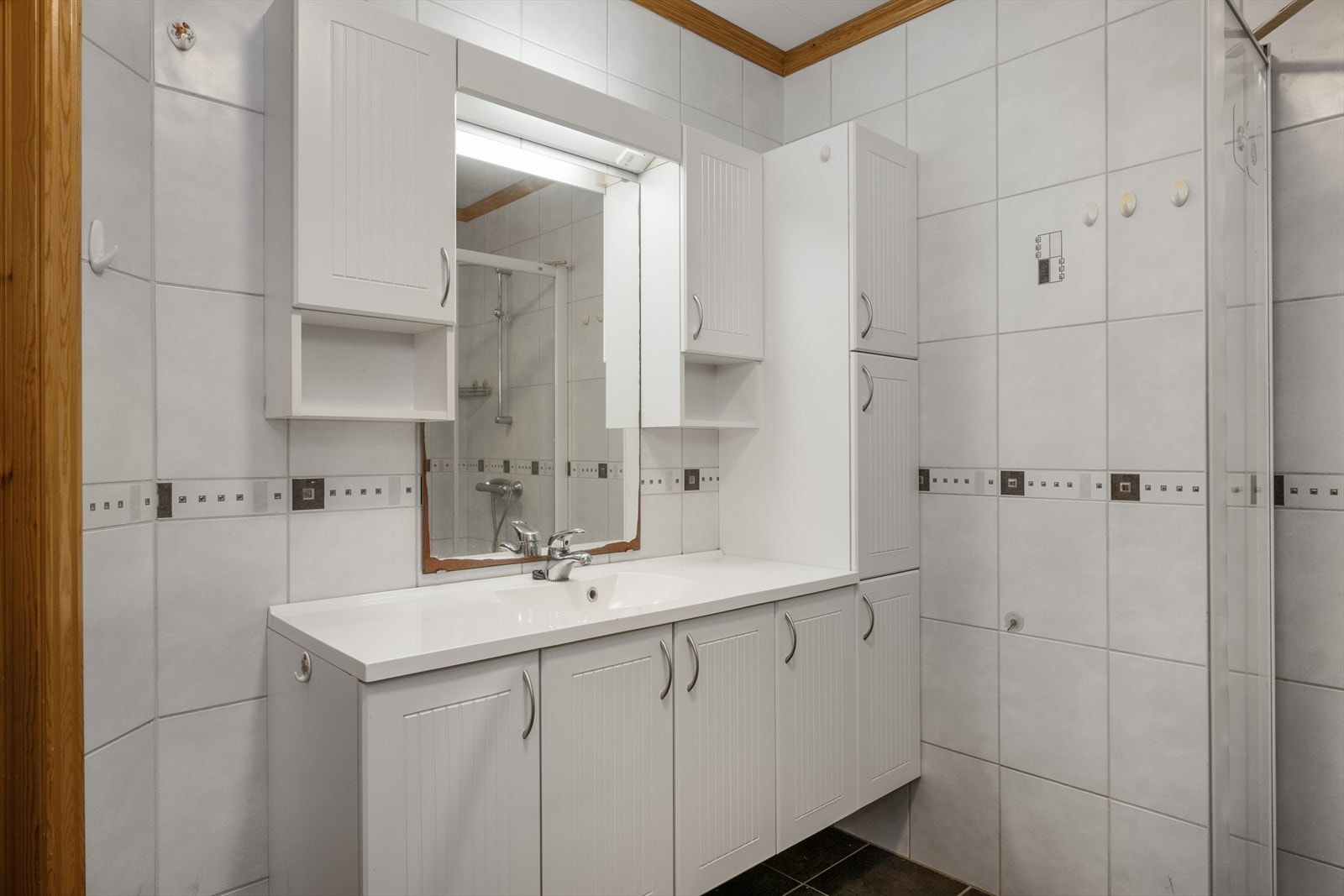 Badet har fliser på gulv og vegger, samt gulvvarme. Romslig innredning gir god oppbevaringsplass. Galleribilde