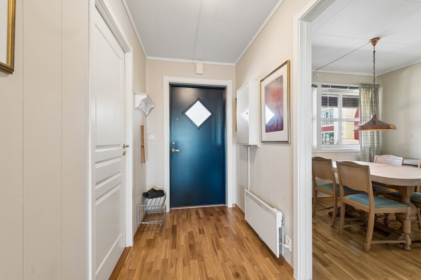 Velkommen inn! Entréen har lysmalte veggflater, parkett på gulvet og åpen garderobeløsning. Galleribilde