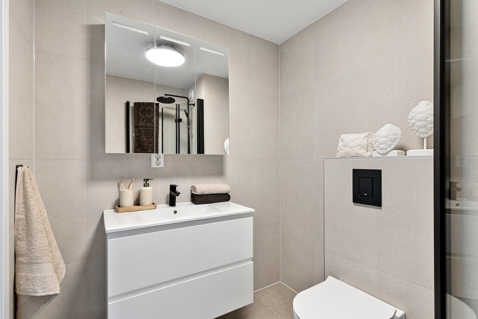 Badet er innredet med vegghengt toalett, servant med tilhørende skap, speil og belysning, samt opplegg for vaskemaskin. Galleribilde