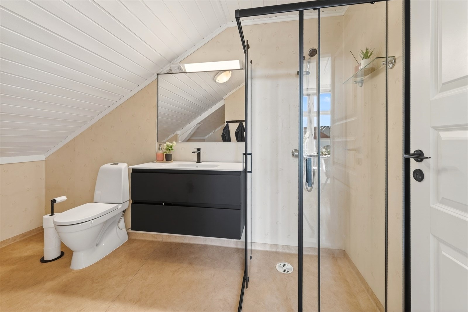Badet er utstyrt med dusjhjørne, heldekkende servant med skuffer, toalett og opplegg til vaskemaskin/tørketrommel Galleribilde