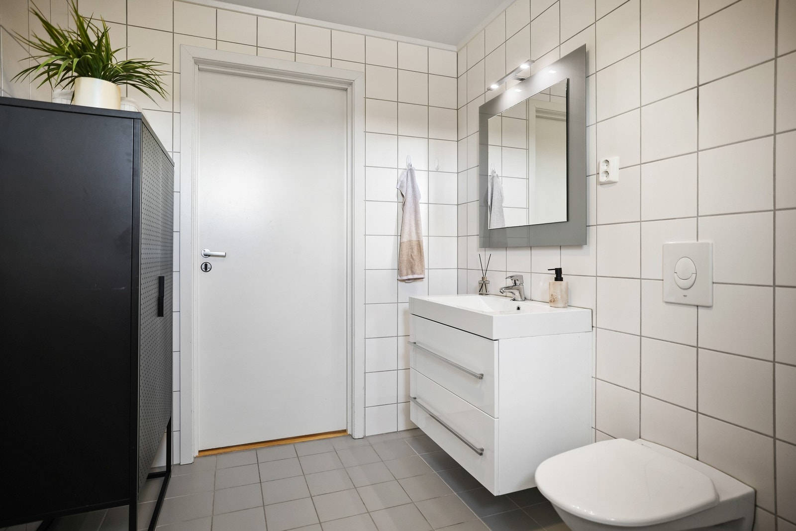 Baderommet inneholder dusjhjørne med dører, vegghengt toalett og opplegg for vaskemaskin. Galleribilde